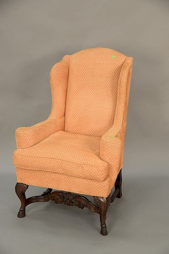 Wing chair with carved hoof feet and carved stretcher.