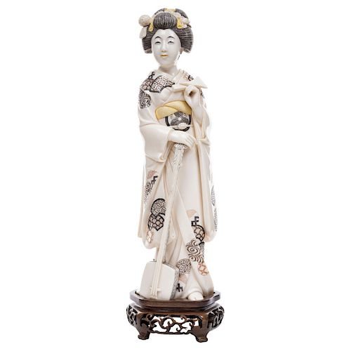 GEISHA PLAYING THE SHAMISEN.  JAPAN, BEGINNING OF THE 20TH CENTURY. Carved ivory model with ink detail, on a wooden stand.