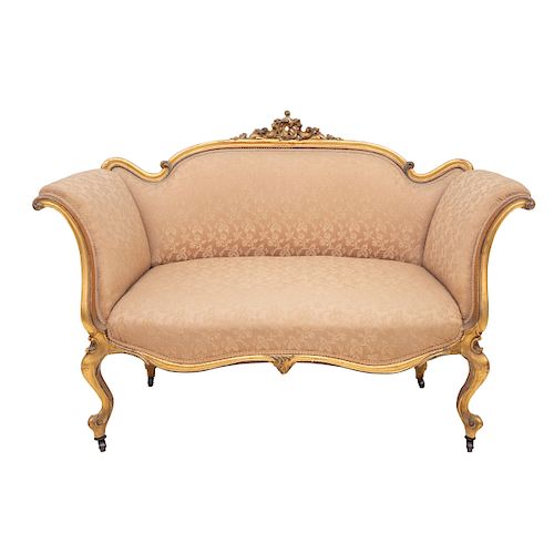 Love seat. Francia, siglo XX. Estilo Luis XV. En madera tallada y dorada, con respaldo y asiento en tapicería color beige.