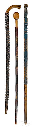 Three carved and painted walking sticks