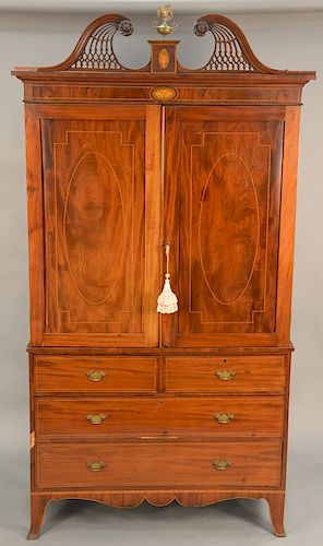 George IV mahogany linen press, having pierced carved broken arch top over two doors with line inlay over two short drawers over two graduating drawer