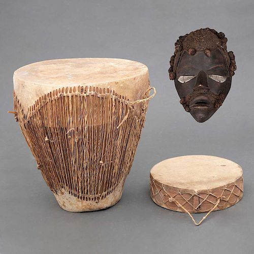 Juego de tambores y máscara. África, Siglo XX. Elaborados en cuero y fibra natural. Consta de: Tambor de piso. Pz: 3