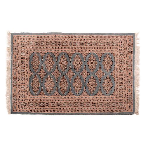 Tapete. Pakistán, siglo XX. Estilo Bokhara. Elaborado en fibras de lana, sobre fondo azul y rosa. Decorado con motivos geométricos.
