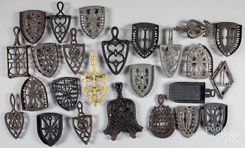 Collection of twenty-five cast iron trivets