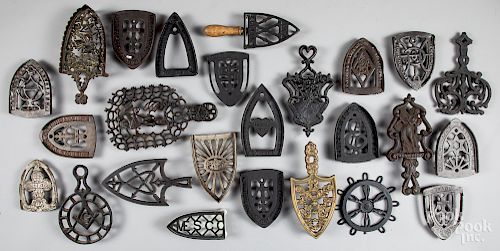 Collection of twenty-five cast iron trivets