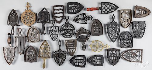 Collection of twenty-eight cast iron trivets