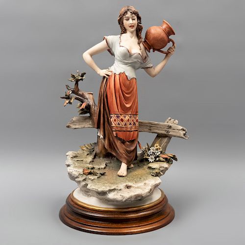 Mujer con cántaro. Italia. Siglo XX. Elaborada en porcelana Capodimonte. Acado gres. Con base de madera. 32 x 22 x 18 cm.