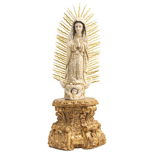 OUR LADY OF GUADALUPE. SPANISH-PHILIPPINE, 20TH CENTURY. Ivory carving with gilded and inked details. With carved and gilded wooden base, with decorat