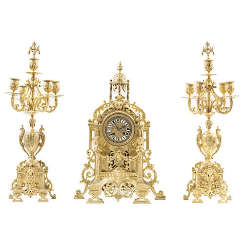 GARNITURE. FRANCE, CIRCA 1900. EMPIRE Style. Gilted bronze clock with brass dial and enamelled Roman numerals. Decorated with vegetal motifs, acanthus