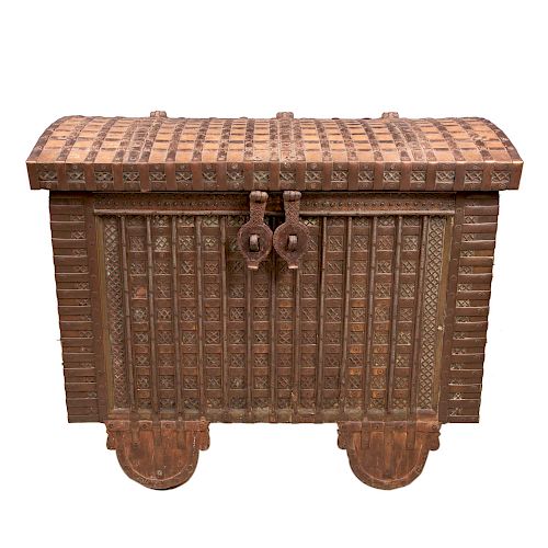Baúl de caudales para lomo de elefante. India, siglo XIX. Elaborado en madera tallada con aplicaciones de soleras de hierro cincelado.