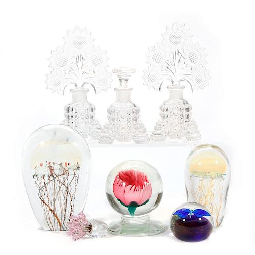 A collection of glass paper weights and perfumes.