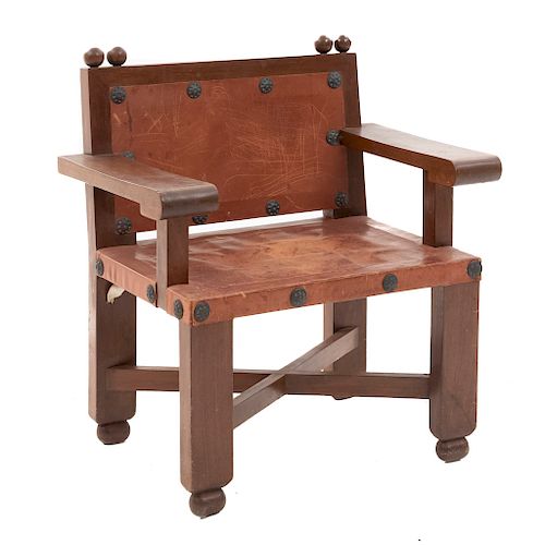 Sillón. Siglo XX. En talla de madera. Con respaldo cerrado y asiento de cuero color marrón, chambrana en "X", fustes lisos.