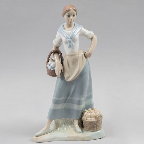 Figura de mujer recolectora. España, siglo XX. Elaborada en porcelana tipo Lladró acabado brillante. 35 cm de altura.