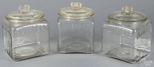 Three clear glass Planters Peanuts counter jars, 20th c., 9 1/2'' h.