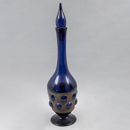Licorera. Siglo XX. Elaborada en vidrio soplado color azul cobalto, con aplicación de falda de lámina. 60 cm de altura.