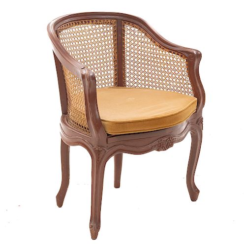 Sillón. Siglo XX. En talla de madera. Con respaldo y paredes de bejuco y asiento con cojín en tapicería color marrón.