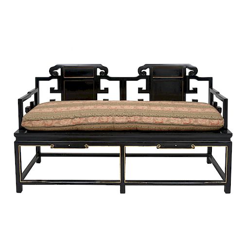 Love seat Siglo XX. Estilo Chinesco. Elaborado en madera tallada ebonizada con cojín en tapicería con cenefas orgánicas.