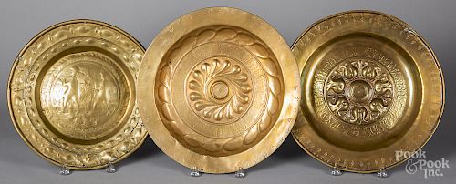 Three Continental embossed brass alms dishes