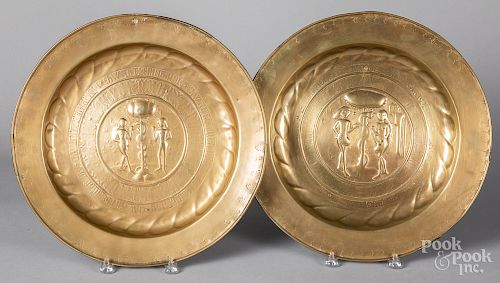 Two embossed brass Adam and Eve alms dishes