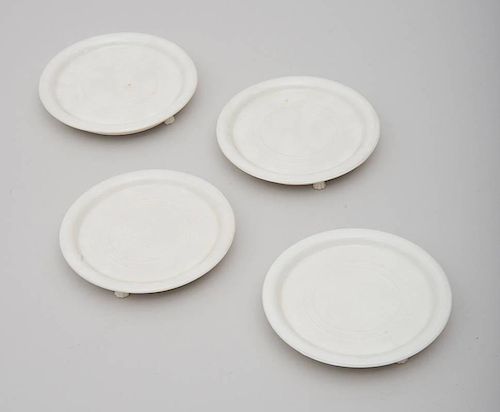 GROUP OF FOUR FOOTED PORCELAIN BOTTLE COASTERS