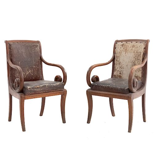 Par de sillones. Siglo XX. En talla de madera. Con respaldos cerrados y asientos acojinados en piel color marrón.