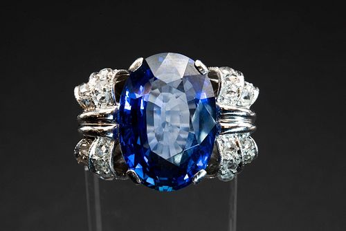 A CEYLON SAPPHIRE AND DIAMOND RING, the large oval cut sapphire set betwee