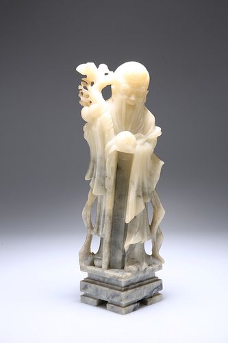 A CHINESE SOAPSTONE FIGURE, 19TH CENTURY, of an Immortal, carved standing h
