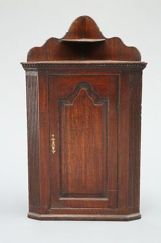 A GEORGE III OAK CORNER CUPBOARD, with fielded arch panel door flanked by f