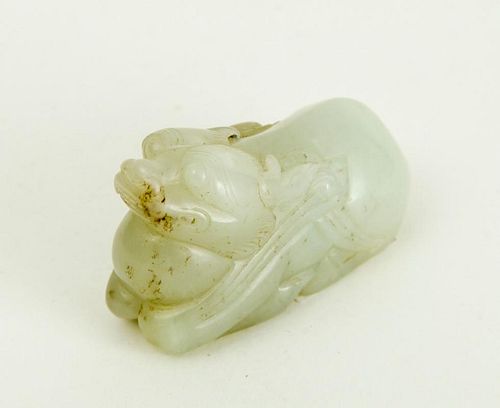 CHINESE CARVED PALE GREEN JADE FIGURE OF A RECUMBENT FU DOG HUGGING A BALL