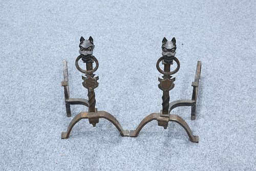 A PAIR OF WROUGHT IRON FIRE DOGS, each beast cast holding a loop in its mou