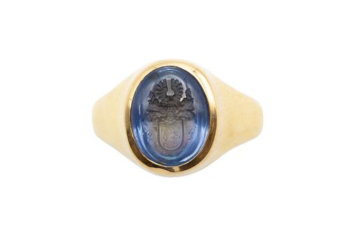 A SAPPHIRE INTAGLIO RING
 The oval plaque incised with a crest, in a polish