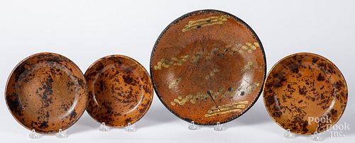 Four redware plates and shallow bowls