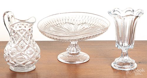 Colorless glass compote, pitcher, and vase.