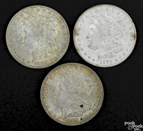 Three Morgan silver dollars, to include an 1879 S, UNC, an 1890, AU, and a 1902 O, UNC.