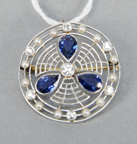 Platinum circular brooch set with three tear drop blue sapphires and seven diamonds, 6.4 grams.