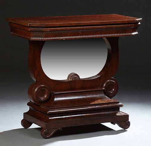 American Classical Carved Mahogany Petticoat Table, 19th c., the canted corner top over a wide skirt on a U-shaped support with a ce...