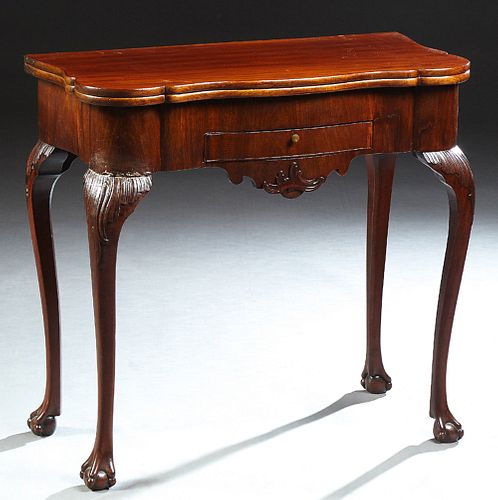 English Georgian Carved Mahogany Games Table, late 18th/ early 19th c., the shaped rounded corner folding top enclosing a compartmen...