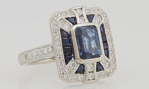 Lady's Platinum Dinner Ring, with a cushion cut 1.3 carat blue sapphire flanked by blue sapphire baguettes over the side, within a b...
