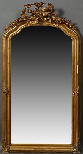French Louis XVI Style Gilt and Gesso Overmantel Mirror, 19th c., the arched serpentine top with an elaborate bird, floral, torch an...