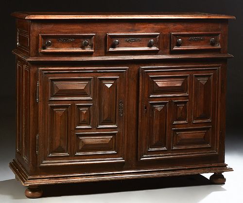 French Provincial Louis XIII Style Carved Walnut Sideboard, 19th c., the stepped top over three frieze drawers, above large cupboard...