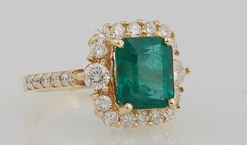 Lady's 14K Yellow Gold Dinner Ring with a 3.1 carat emerald, atop a border of round diamonds, the shoulders of the band also mounted...
