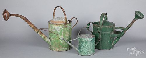 Three green painted tin watering cans