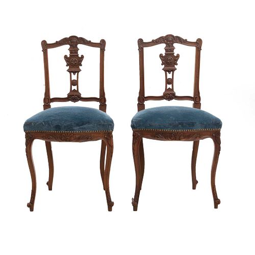 Par de sillas. Francia. Siglo XX. Estilo Luis XV. En talla de madera de nogal. Con respaldos semiabiertos y asientos en tapicería azul.