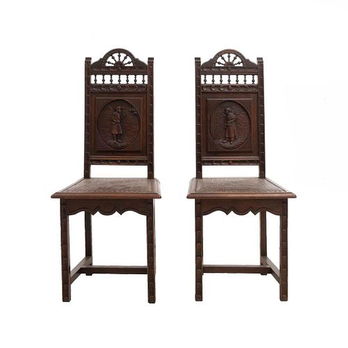 Par de sillas. Francia. Siglo XX. Estilo Bretón. En talla de madera de roble. Con respaldos semiabiertos y asientos tipo piel.