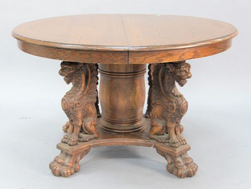 Round oak dining table having pedestal base with winged griffin supports over large paw feet, having two 18" leaves, ht. 29", dia. 48", top open 48" x