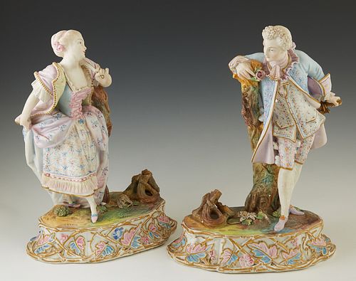 Pair of Continental Polychromed Biscuit Porcelain Figures, 19th c., of a couple in 18th c. costume, on relief leaf decorated oval ba...