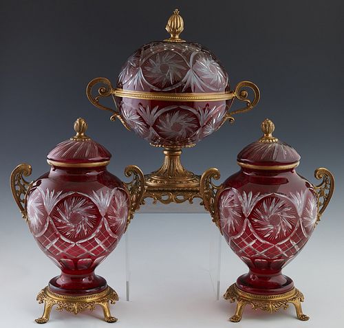 Three Piece Ruby Cut-to-Clear Glass and Brass Garnitures, 20th c., consisting of a large covered handled circular bowl on a brass socle support on fou