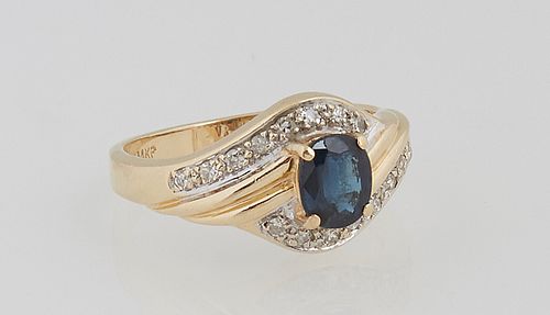 Lady's 14K Yellow Gold Dinner Ring, with an oval one carat blue Sapphire, atop a bypass band with 10 channel set 3 point diamonds on two sides, total 