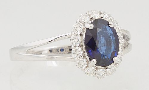 Lady's 14K White Gold Dinner Ring, with an oval 1.24 ct. blue sapphire atop a border of round diamonds, on a split shoulder band, total diamond wt.- .
