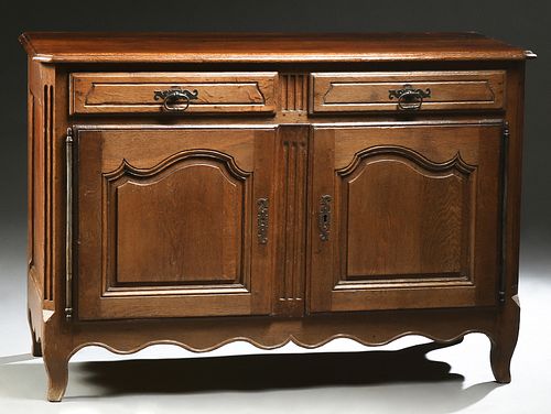 French Louis XV Style Carved Oak Sideboard, 19th c., the canted corner stepped reeded edge top above two drawers over two arched fielded panel doors w